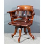 An early 20th Century stained wood swivel office armchair with horseshoe shaped back, curved crest