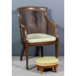 An Edwardian mahogany framed Bergere armchair of "Georgian" design, inlaid with stringings and