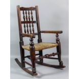 A 19th Century child's ash and fruitwood spindle back rocking chair with rush seat, on turned