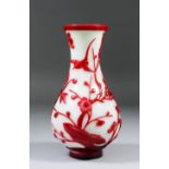 A Chinese red overlay glass baluster shaped vase, the red overlay cut with a bird on rockwork with