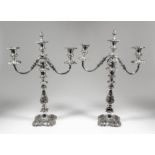 A pair of plated pillar candlesticks with two branch candelabra fitments, with scroll cast mounts,