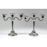 A pair of Elizabeth II silver three branch candelabra with leaf cast mounts, urn pattern sconces and