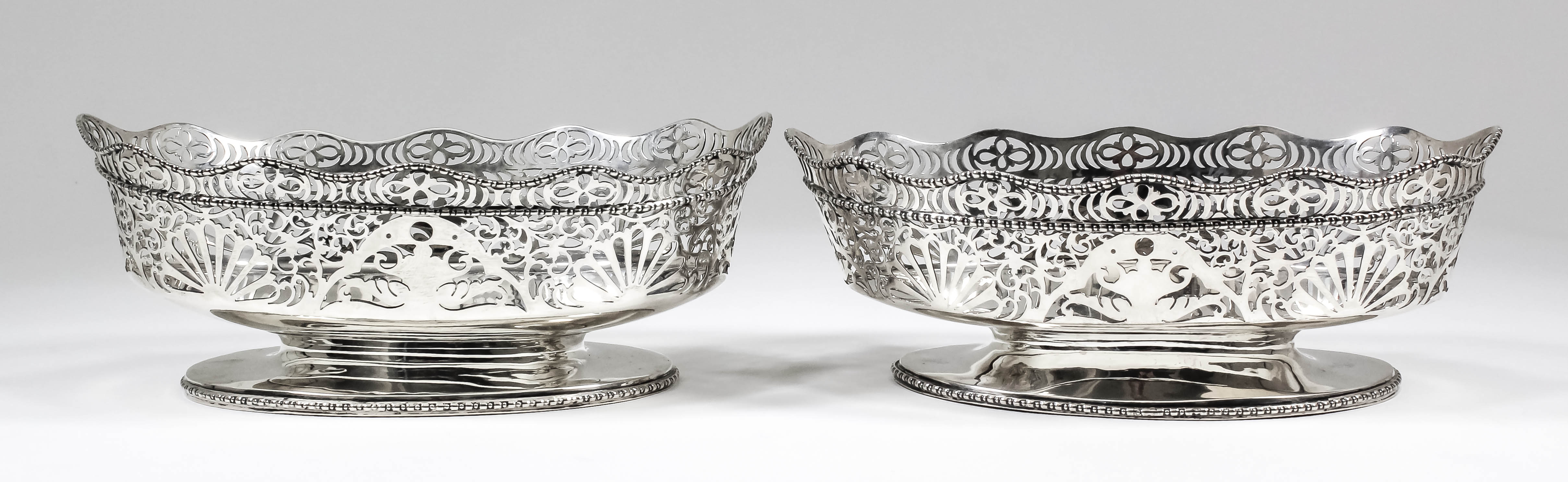 Two pierced George V silver oval bowls, the shaped rims with bead mounts, the sides pieced with