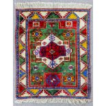 An Kazak Fakhralu rug woven in colours with a bold central medallion filled with cross motif and
