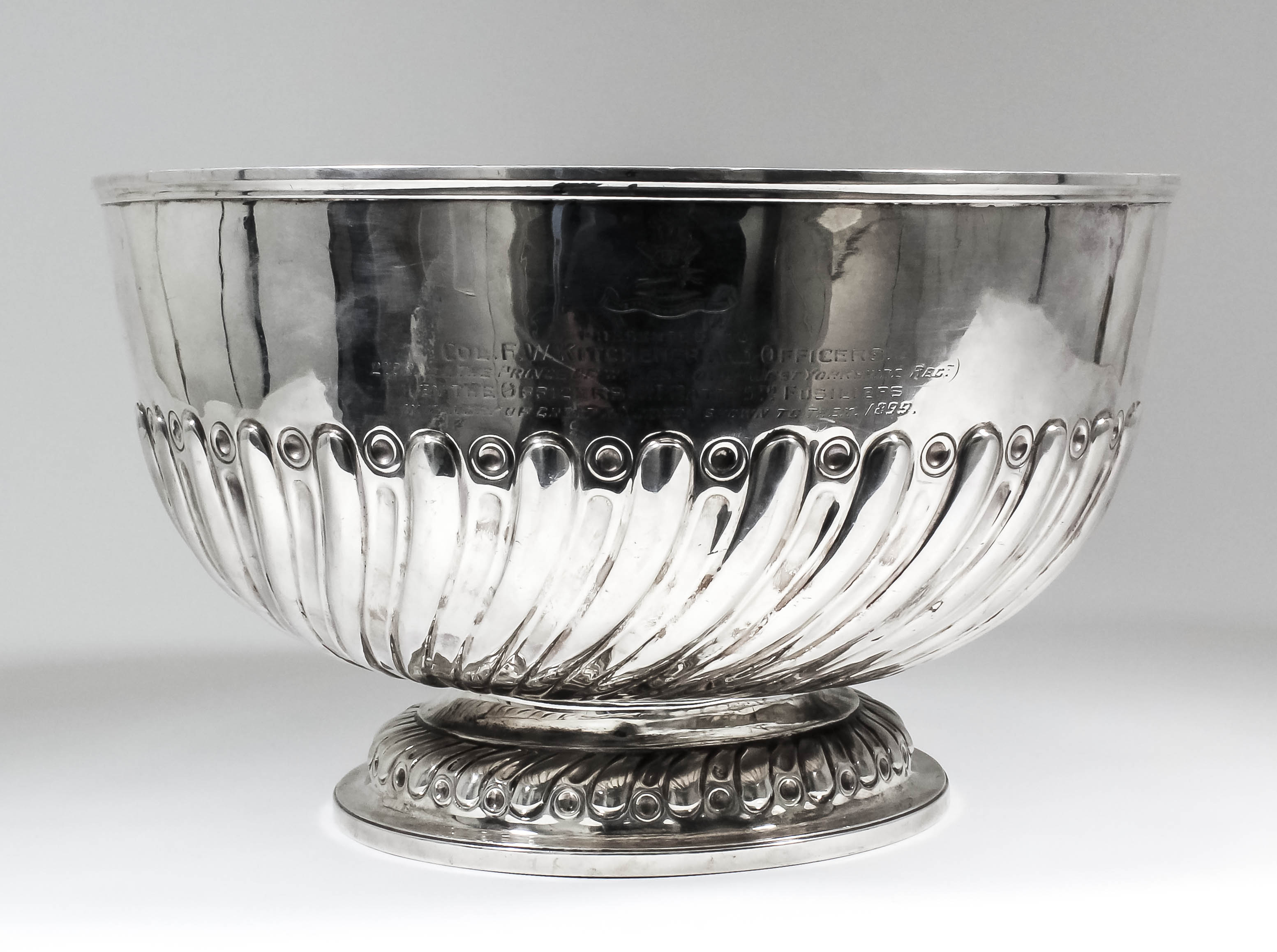 A late Victorian silver Regimental circular punch bowl with moulded rim, part reeded and fluted