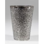 A near Eastern silvery metal cylindrical beaker of tapered form, cast with scroll and floral