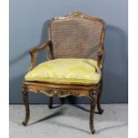 A French walnut and parcel gilt framed open arm fauteuil, the shaped and moulded back with scroll