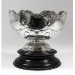 A George V silver circular rose bowl, the shaped rim cast with scroll ornament, the body embossed