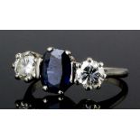 A modern 18ct white gold sapphire and diamond three stone ring, the central oval cut sapphire of