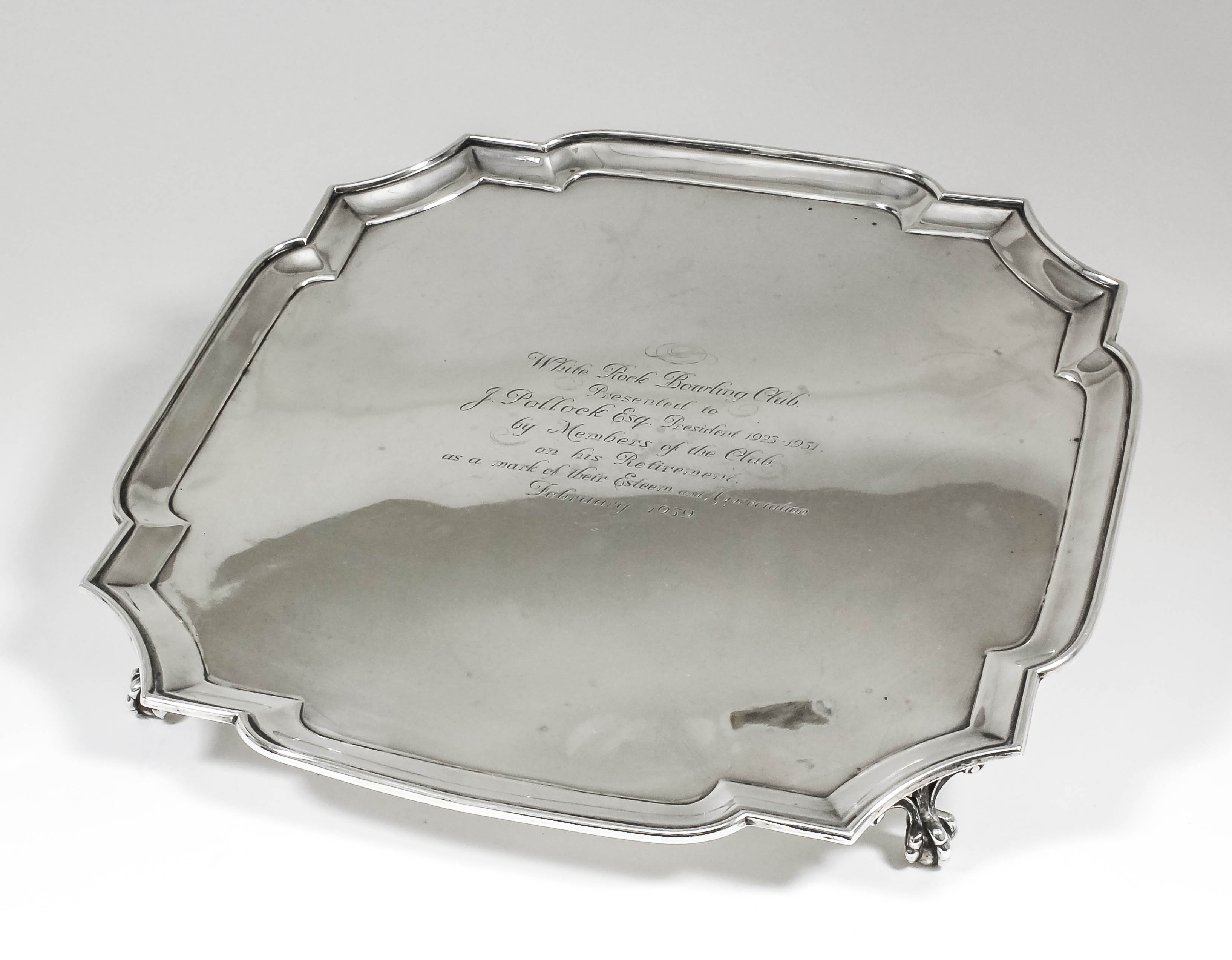 A George V silver square salver with shaped and moulded rim, on four claw and ball feet, 13.75ins