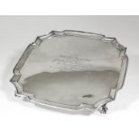 A George V silver square salver with shaped and moulded rim, on four claw and ball feet, 13.75ins