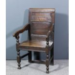 A panelled oak armchair of "17th Century" design with moulded crest rail, shaped arms and wood seat,