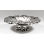 A William IV silver circular sexfoil fruit dish with turned-over rim, embossed with bold leaf scroll