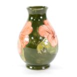 A WALTER MOORCROFT POTTERY VASE OF BALUSTER SHAPE, the green ground tube lined with pink flowers,