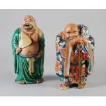 TWO JAPANESE PART GLAZED PORCELAIN FIGURES OF HOTEU, one modelled wearing green robes and holding
