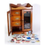 AN EDWARDIAN OAK SMOKER'S CABINET ENCLOSED BY TOW BEVELLED GLASS INSET DOORS, THE INTERIOR WITH