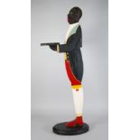 EARLY TWENTIETH CENTURY PAINTED WOOD FIGURAL DUMB WAITER, typical form, modelled holding a small