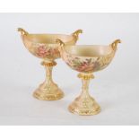 PAIR OF EARLY TWENTIETH CENTURY ROYAL WORCESTER BLUSH PORCELAIN TWO HANDLED PEDESTAL DISHES, of boat