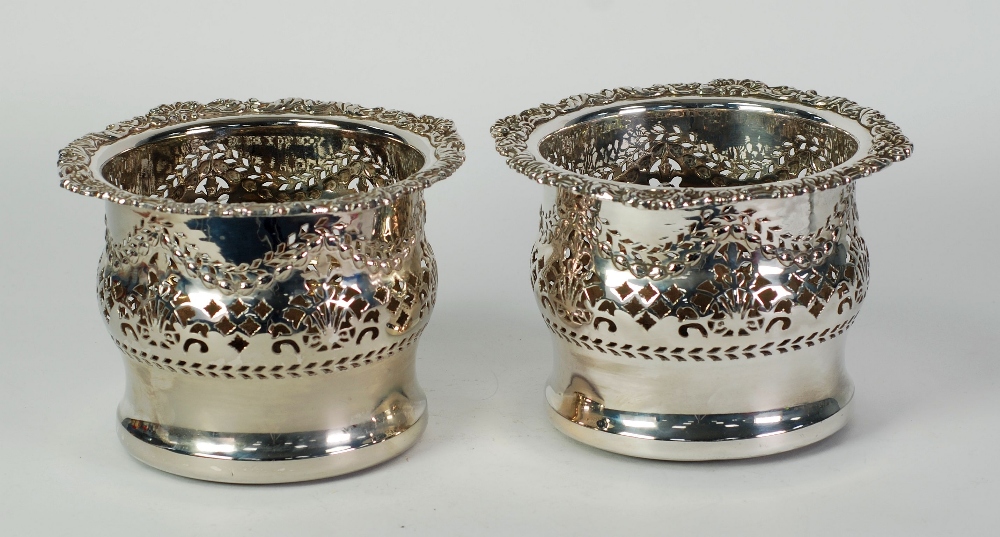 A PAIR OF LATE VICTORIAN/EDWARDIAN PLATED ON COPPER PIECED WINE BOTTLE HOLDERS, with stamped foliate