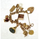 A 9ct GOLD CHARM BRACELET, INCLUDING AN 18ct GOLD FOB SEAL, 56.3gms in all gross