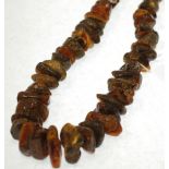 ROUGH NATURAL AMBER NECKLACE, formed of 60 graduated amber beads, 12 ½" (31.7cm) long, 219g