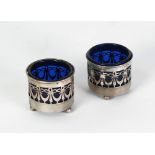 PAIR OF SILVER OPEN SALTS, circular with pierced swag pattern sides, raised on three ball feet,