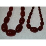 TWO RED BAKELITE BEAD NECKLACES, one formed of 31 graduated oval beads, with stamped 9ct gold barrel