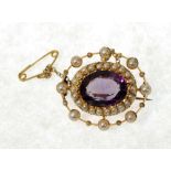 AN EDWARDIAN 15ct GOLD BROOCH, set with a central amethyst within a surround of seed pearls