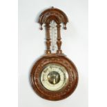 EDWARDIAN CARVED BLONDWOOD CASED ANEROID BAROMETER, with mercury thermometer to the trunk (a.f.), 13