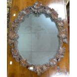 WELL CARVED RUSTIC OAK WALL MIRROR, the oval plate within a frame carved