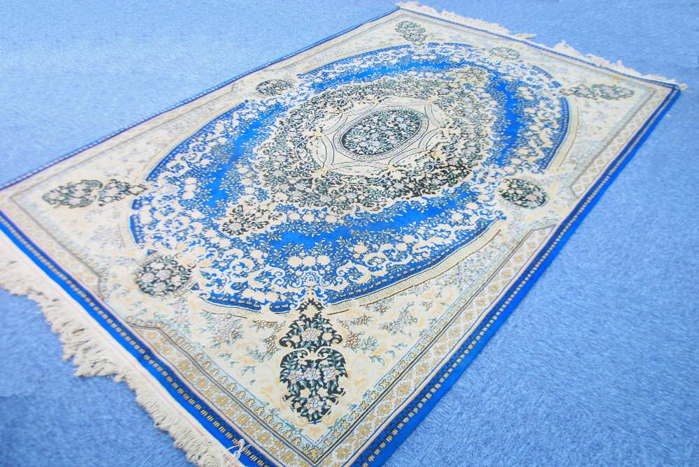 KIRMAN CARPET, principally dark blue and fawn having a large and elaborate floral centre medallion