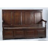 LATE EIGHTEENTH CENTURY NORTH WALES JOINED OAK BOX SETTLE, the four panelled back with carved