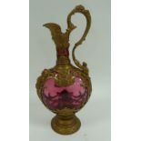 NINETEENTH CENTURY GILT METAL CASED CRANBERRY GLASS PEDESTAL CLARET JUG, of oval form with mask