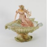 EARLY TWENTIETH CENTURY ROYAL DUX MOULDED PORCELAIN FIGURAL PEDESTAL DISH, painted in muted tones