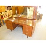 A SMALL CIRCA 1960's TEAKWOOD CONVEX FRONTED KNEEHOLE DRESSING TABLE