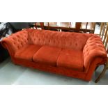 A THREE SEATER CHESTERFIELD SETTEE COVERED IN RED FABRIC