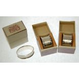 THREE INDIVIDUALLY BOXED GEORGE V ENGINE TURNED SILVER NAPKIN RINGS, comprising; a PAIR with