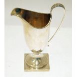 EARLY 20th CENTURY SILVER GEORGIAN STYLE HELMET SHAPE CREAM JUG with loop handle and square base,