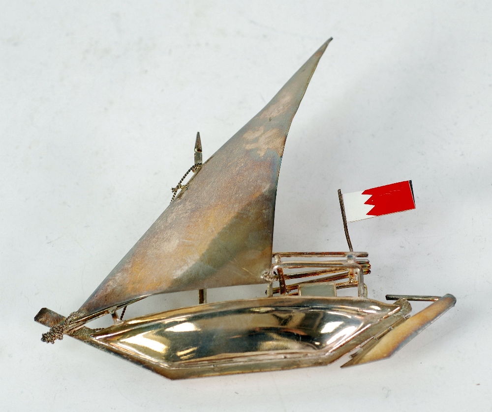 SILVER METAL MODEL OF A DHOW, with enamelled flag, 6 ¼" (15.8cm) long, 3.05oz
