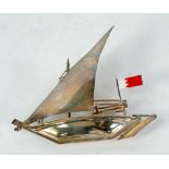 SILVER METAL MODEL OF A DHOW, with enamelled flag, 6 ¼" (15.8cm) long, 3.05oz