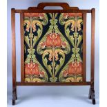 AN EDWARDIAN MAHOGANY FRAMED FIRE SCREEN, enclosing an Arts and Crafts machine work tapestry in