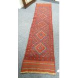 MESHWANI HAND KNOTTED WOOL RUNNER, WORKED IN BLUE AND RED WITH A CENTRAL ROW OF FIVE DIAMOND