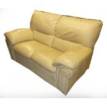 A CREAM COLOURED TWO SEATER LEATHER SETTEE