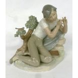 LLADRO FIGURE, YOUNG MAN RECLINING ON GROUND PLAYING A FLUTE, 8" HIGH (SLIGHT FAULTS)