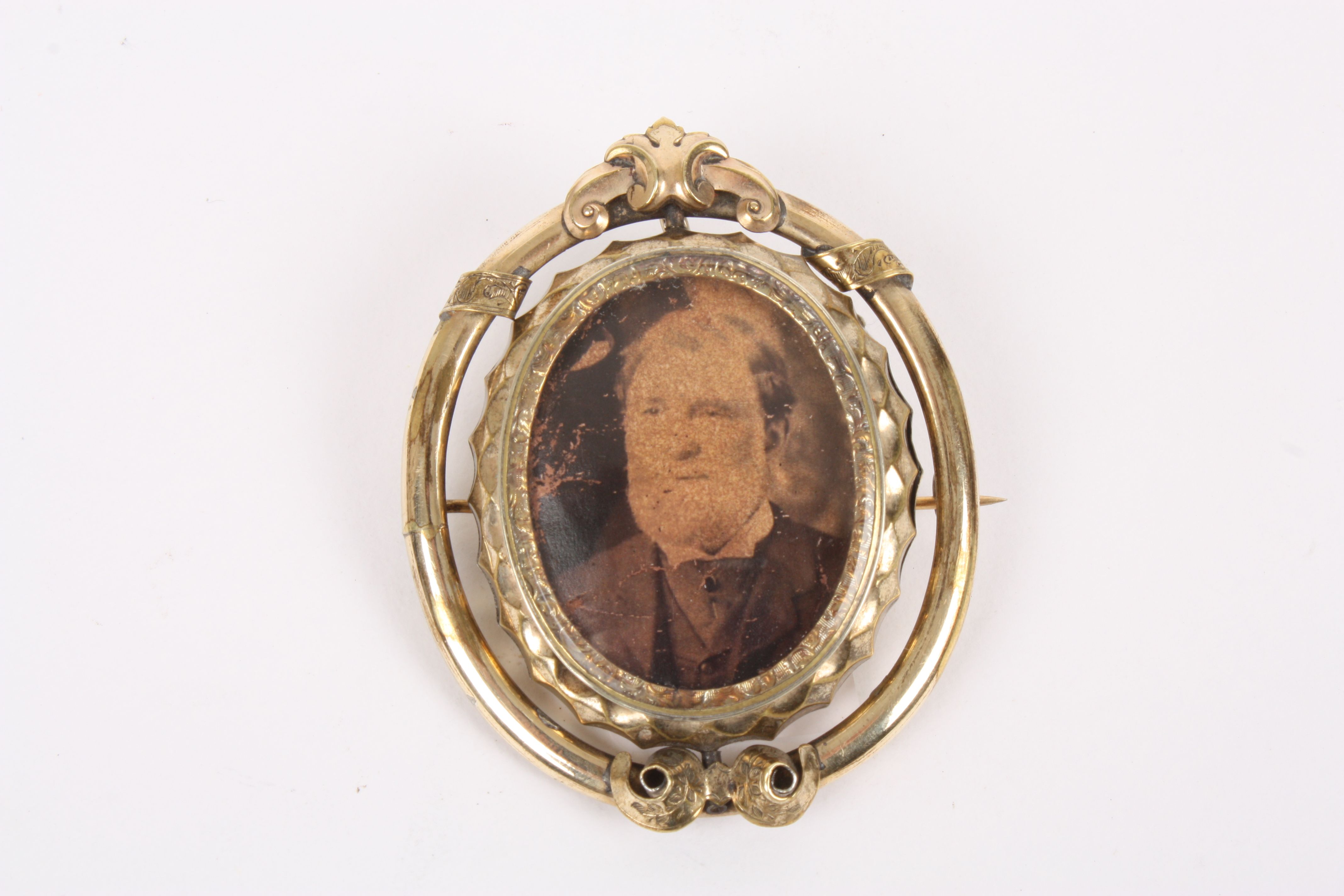 A Victorian pinchbeck reversible portrait brooch
the scrolled frame set with reversible oval panel.,