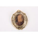A Victorian pinchbeck reversible portrait brooch
the scrolled frame set with reversible oval panel.,