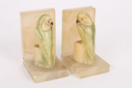 A pair of 1930s carved onyx and hardstone bookendsmodelled as parakeets seated on blocks, with