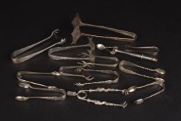 A collection of silver and silver plated sugar nips and tongsof various shapes and sizes.,