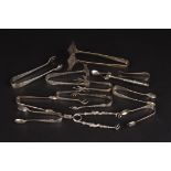 A collection of silver and silver plated sugar nips and tongs
of various shapes and sizes.,