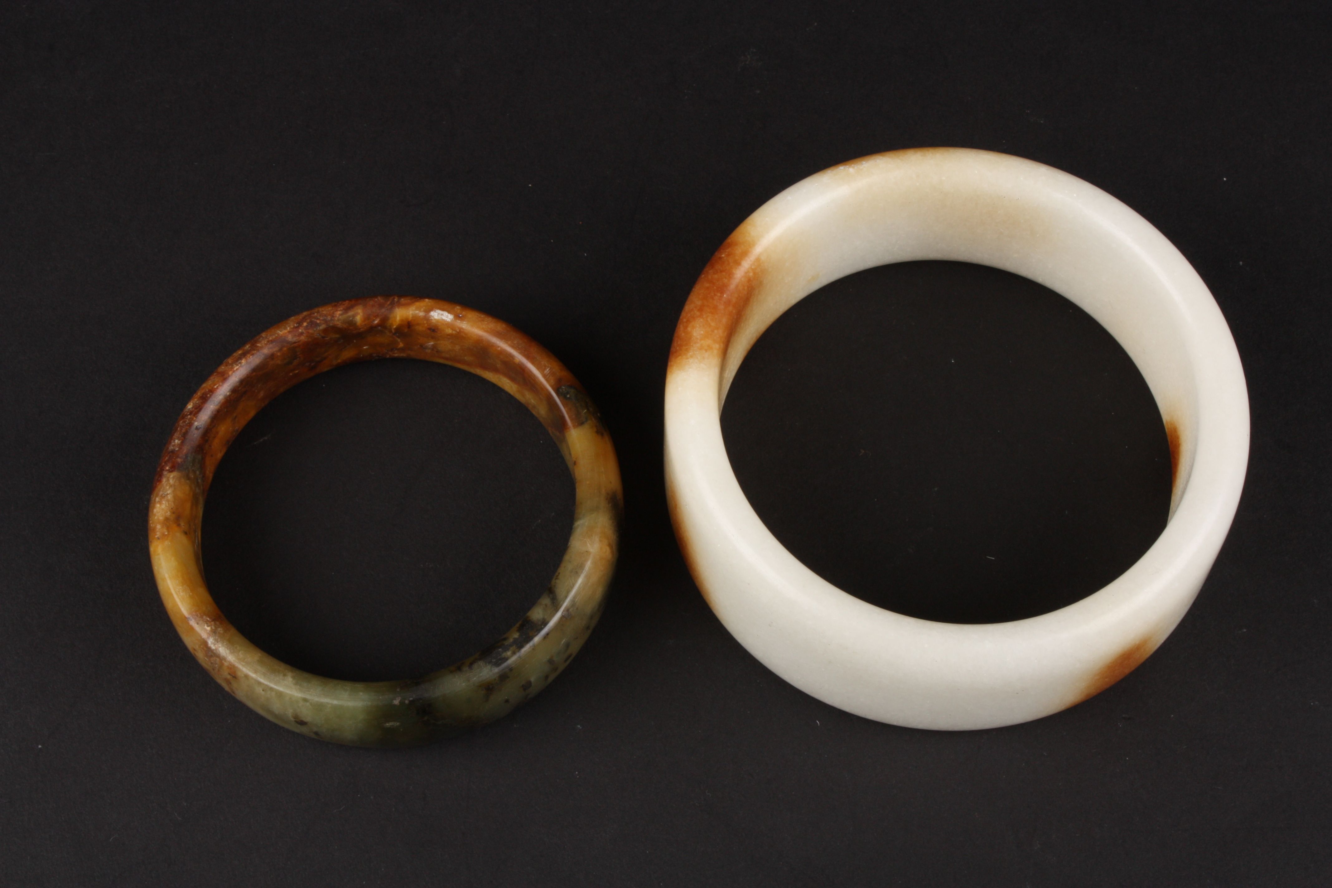 A large 20th Century Chinese white and brown polished stone bangle and another spinach and ochre - Image 2 of 2